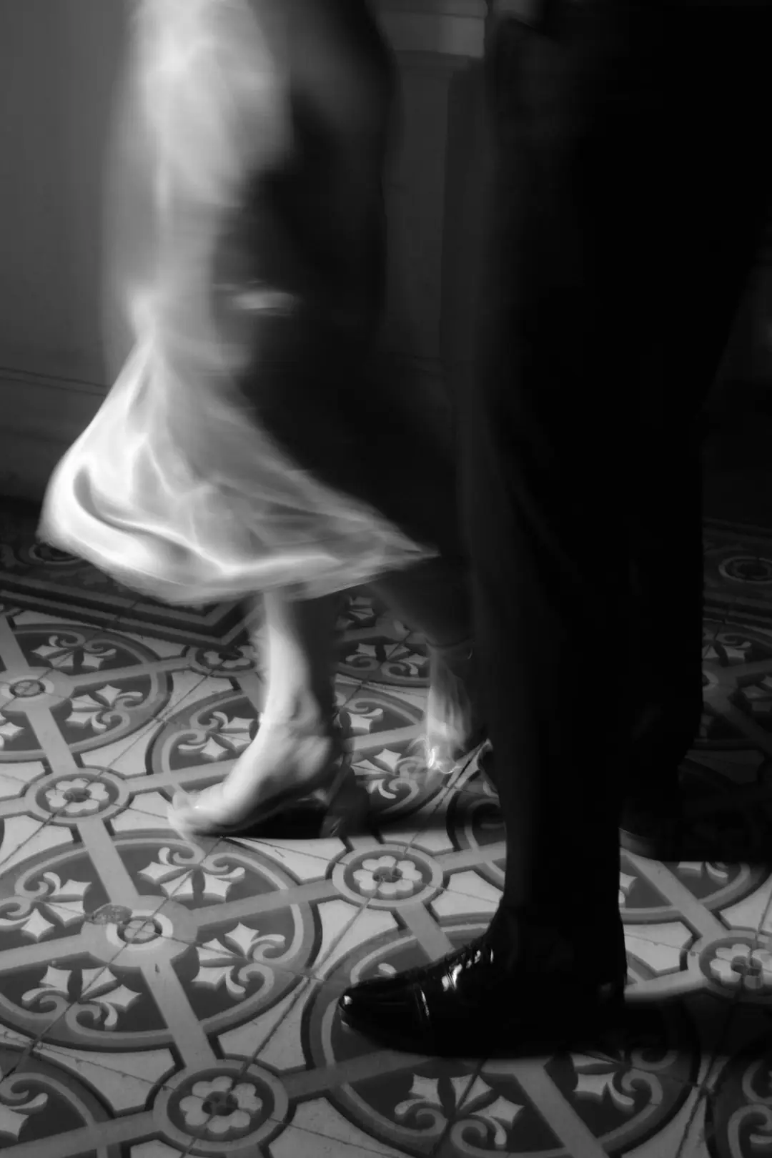 A first dance on a tiled floor, in black and white