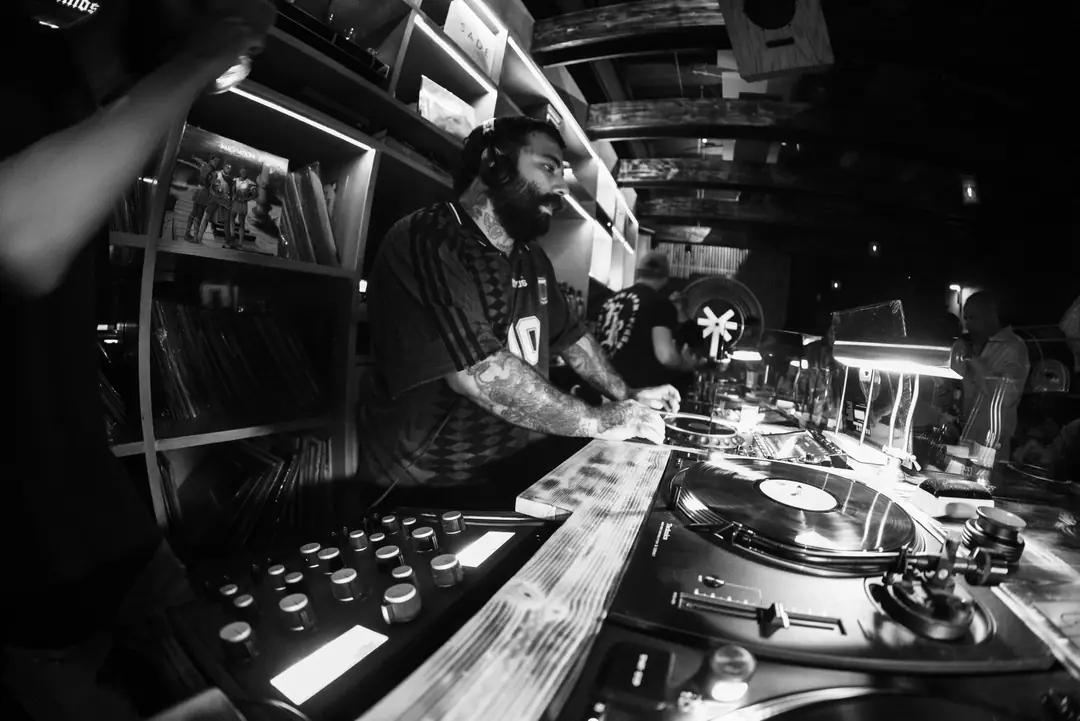 A bar lined with records, the DJ behind it